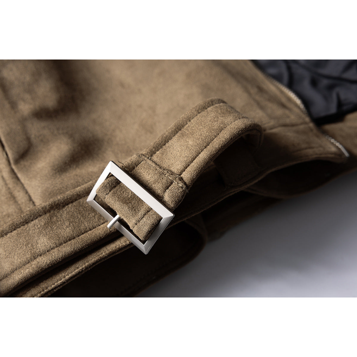 Close-up of a brown jacket waist strap threaded through a rectangular silver buckle.