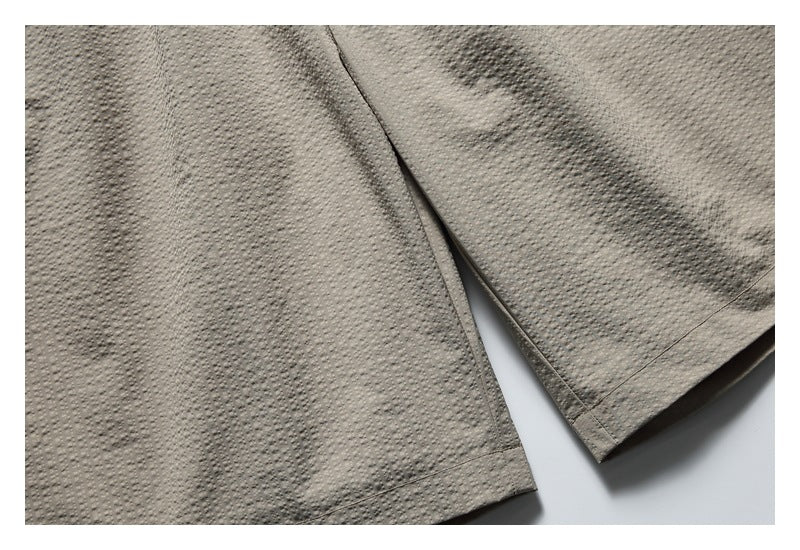 Close-up of the taupe shorts' dotted fabric and stitched leg hems.
