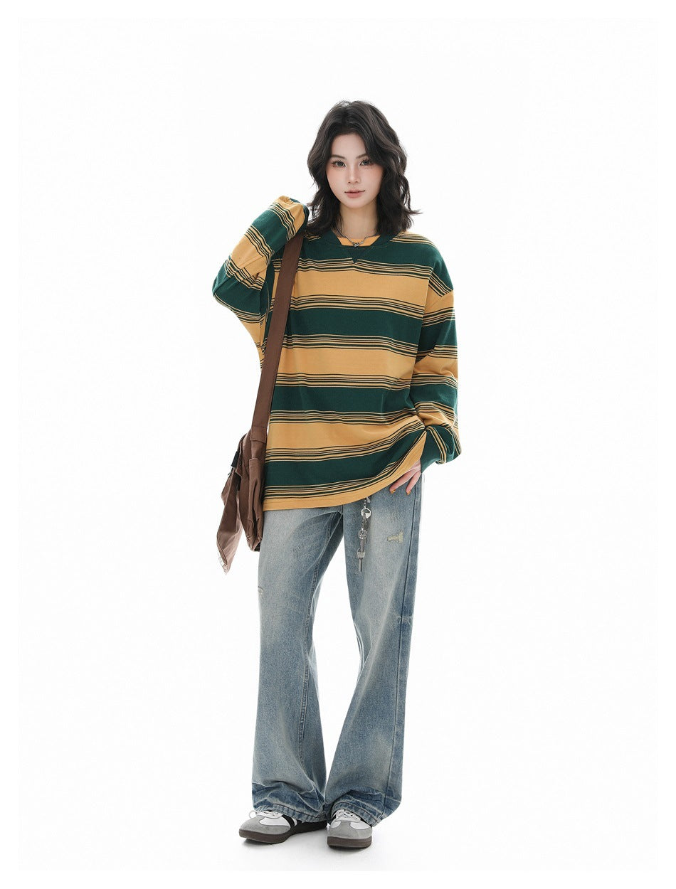 Model wearing a loose green and mustard striped long-sleeve shirt with light blue jeans, shown from the front.