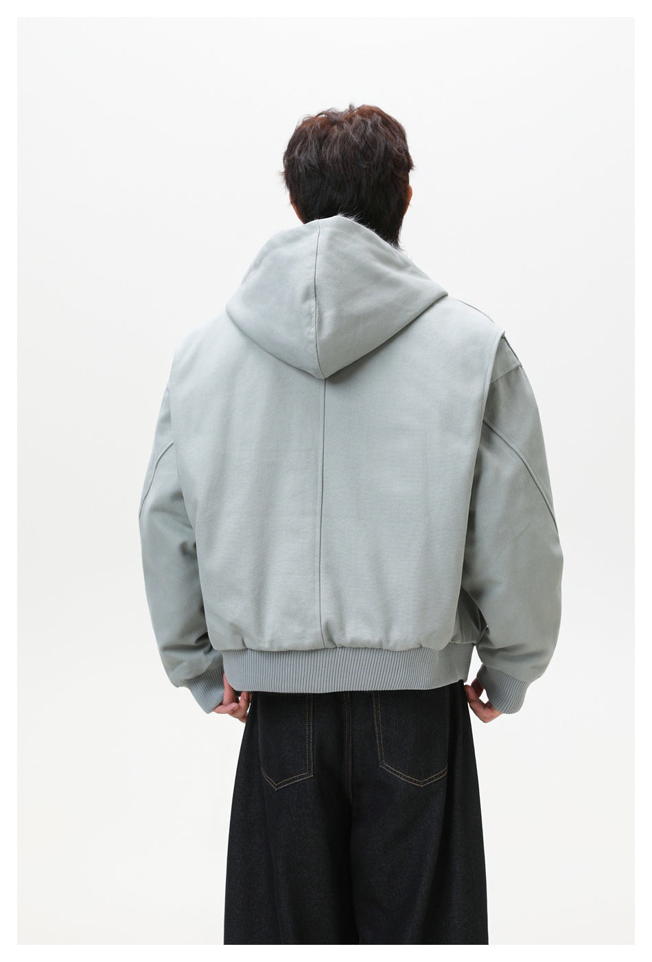Rear view of a model wearing a light gray hooded jacket with a ribbed hem and cuffs.