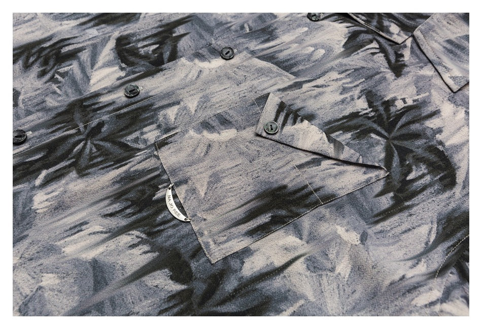 Close-up of the shirt front and buttoned flap chest pocket in gray and black abstract print.