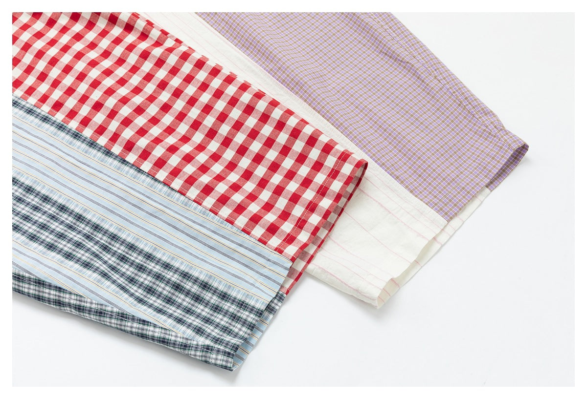 Close-up of overlapping garment panels in red gingham, blue stripes, dark green plaid, white with pink stripes, and lavender