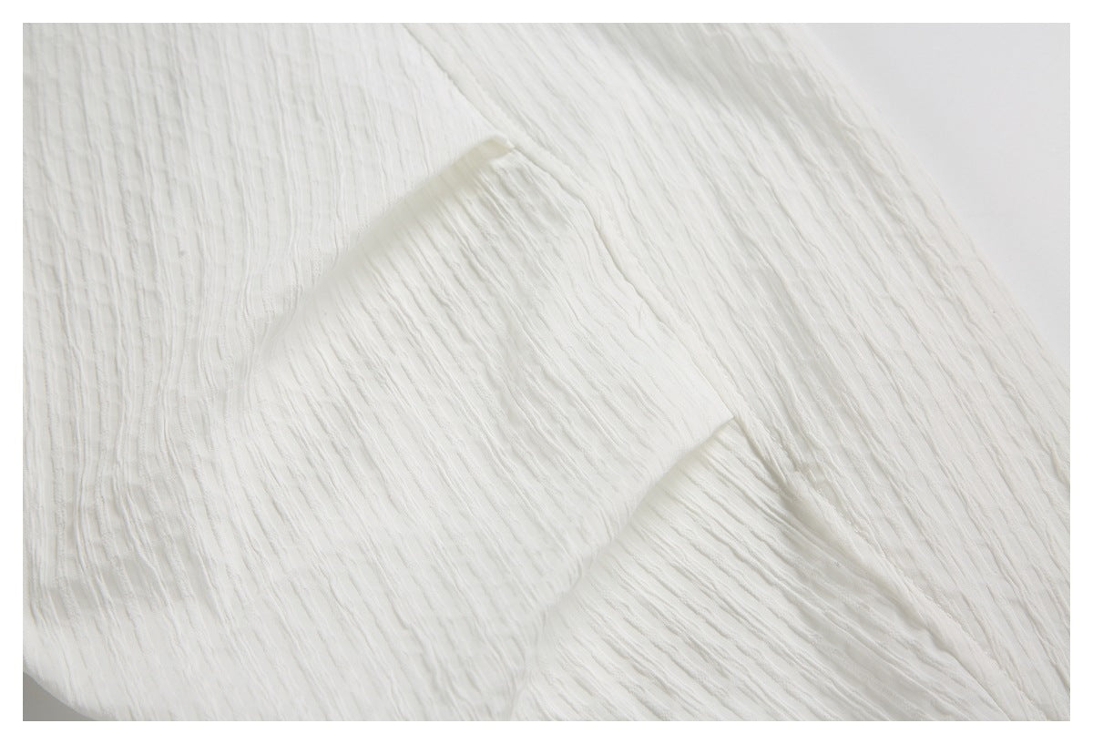 Close-up of white crinkled fabric with a folded, stitched edge.