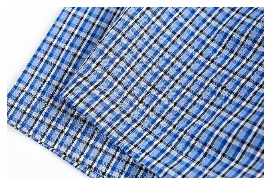 Close-up of blue plaid fabric showing a folded edge and parallel stitching.