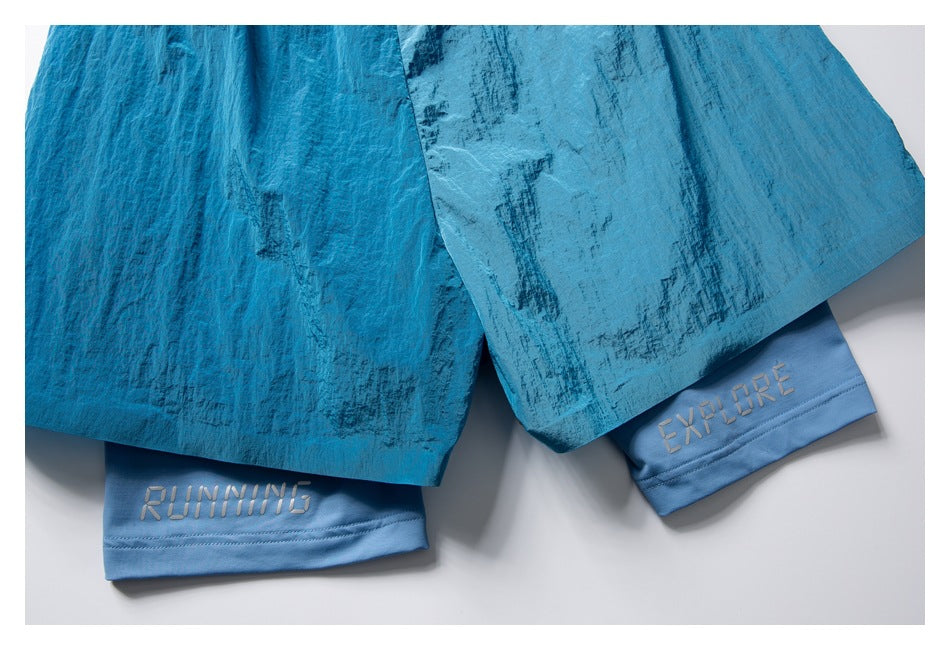 Close-up of turquoise shorts over light blue inner shorts embroidered with RUNNING and EXPLORE.