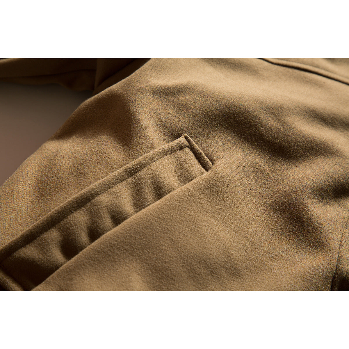 Close-up of a diagonal welt pocket on a camel-brown coat.