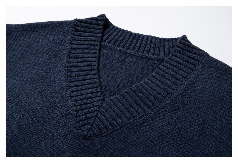 Close-up of a dark navy knit sweater's ribbed V-neck collar and body.