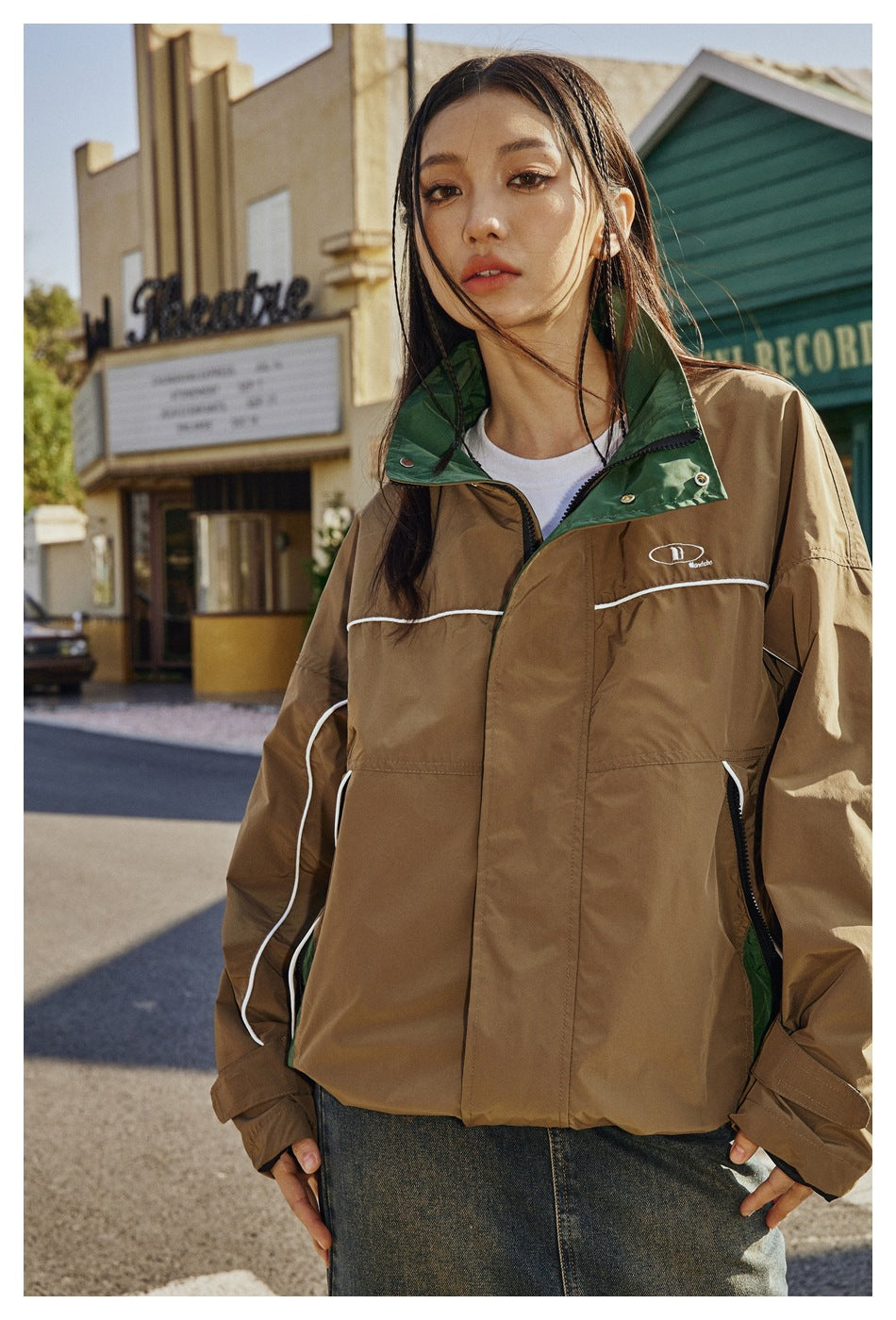 Model wearing a brown jacket with a green stand collar, white piping, and a front zip closure.