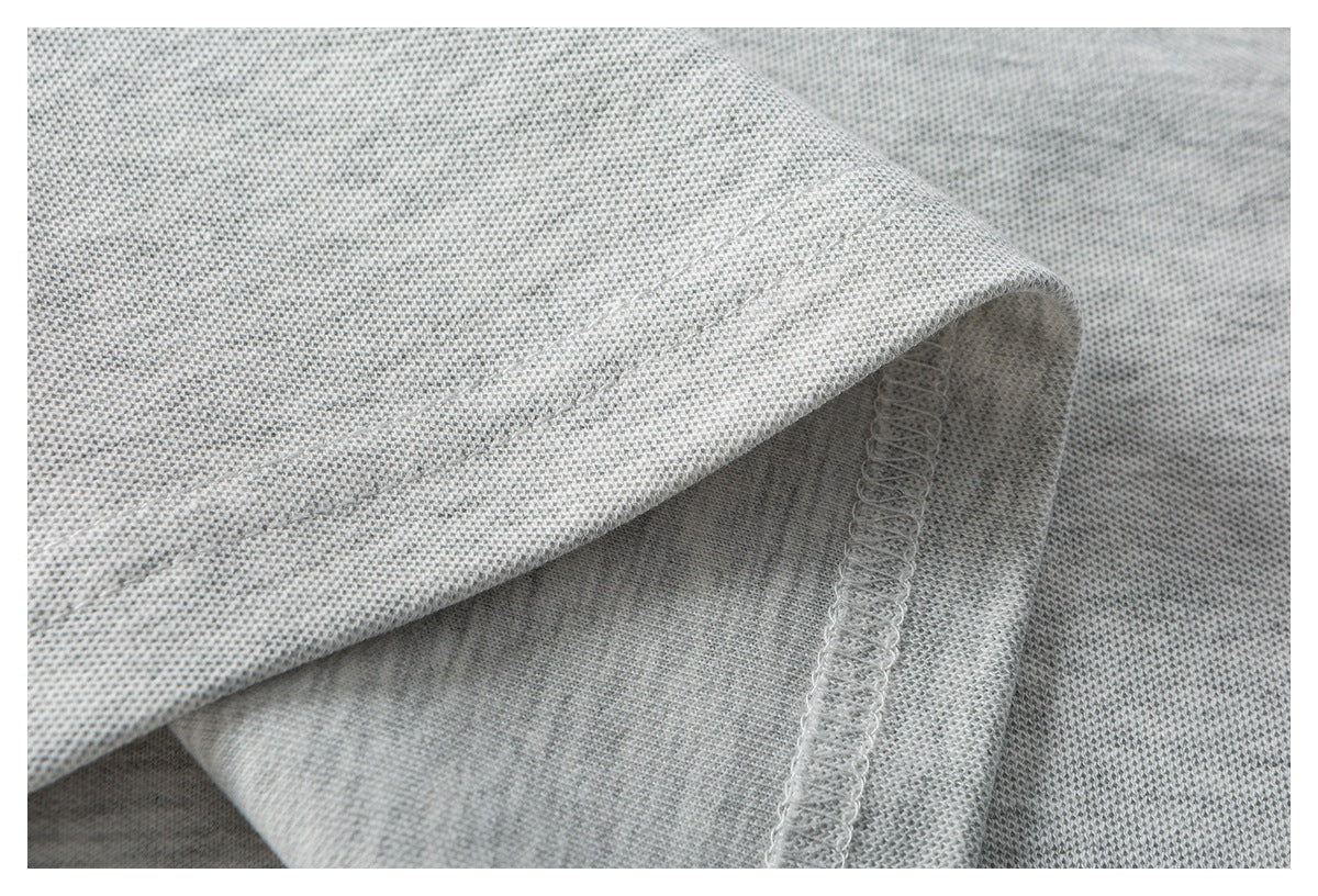 Close-up of a folded light gray knit garment edge with visible overlock stitching.