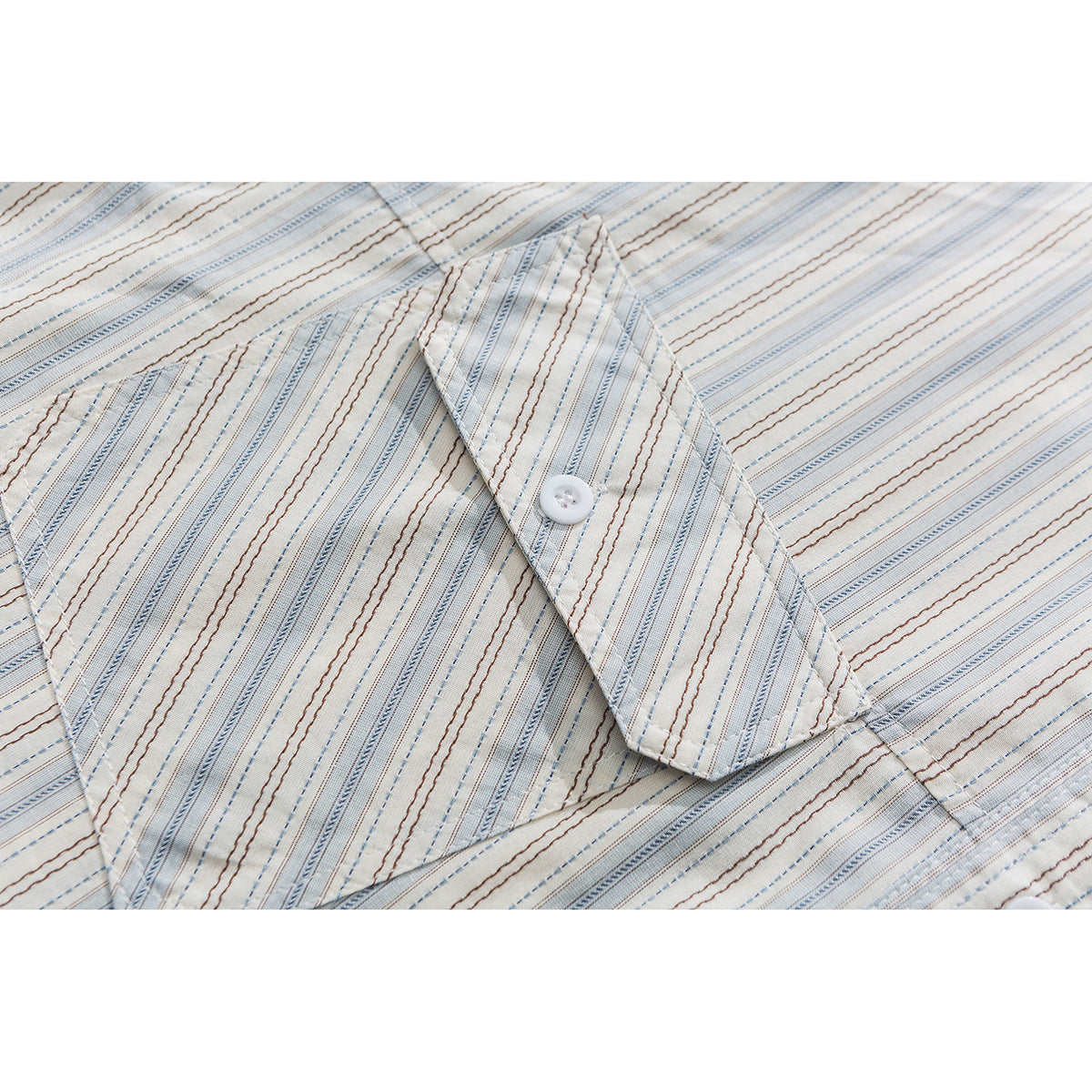 Close-up of the shirt's striped chest pocket and buttoned flap on cream fabric.
