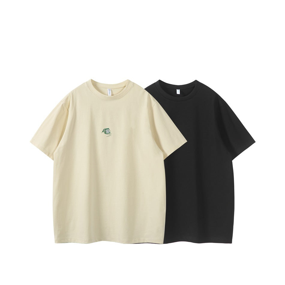 Front view of two short-sleeve crew-neck T-shirts, one cream with a small green chest graphic and one plain black.