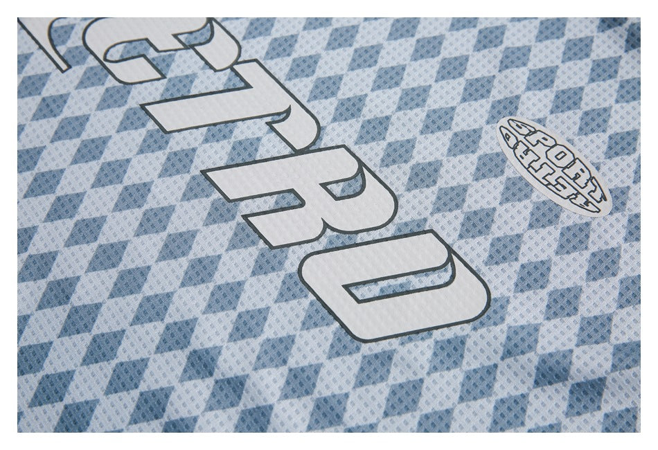 Close-up of large white outlined lettering and an oval emblem on a blue diamond-patterned jersey.