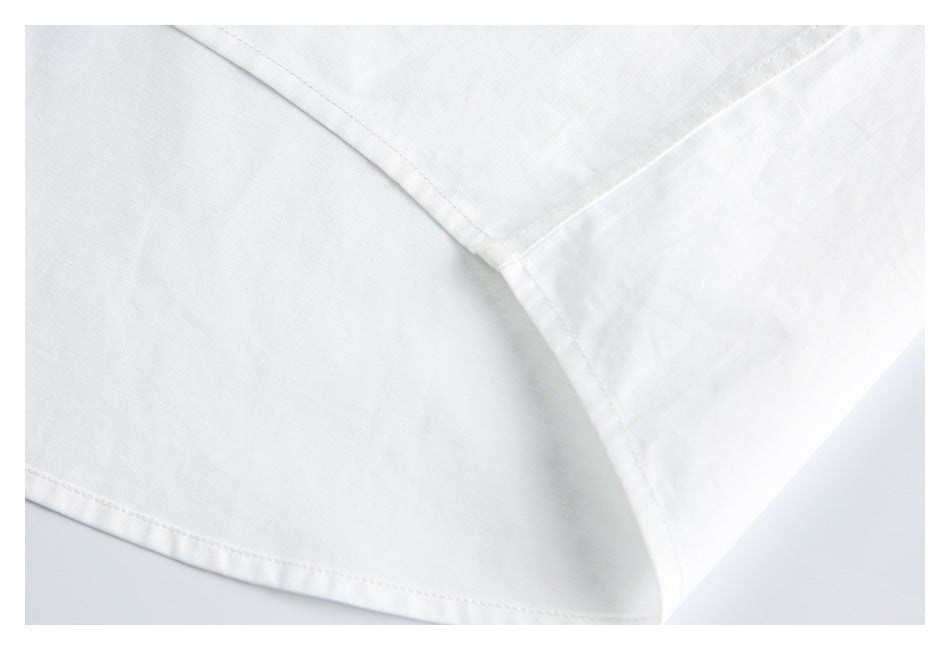 Close-up of stitching and a curved seam near the hem and side of a white shirt.