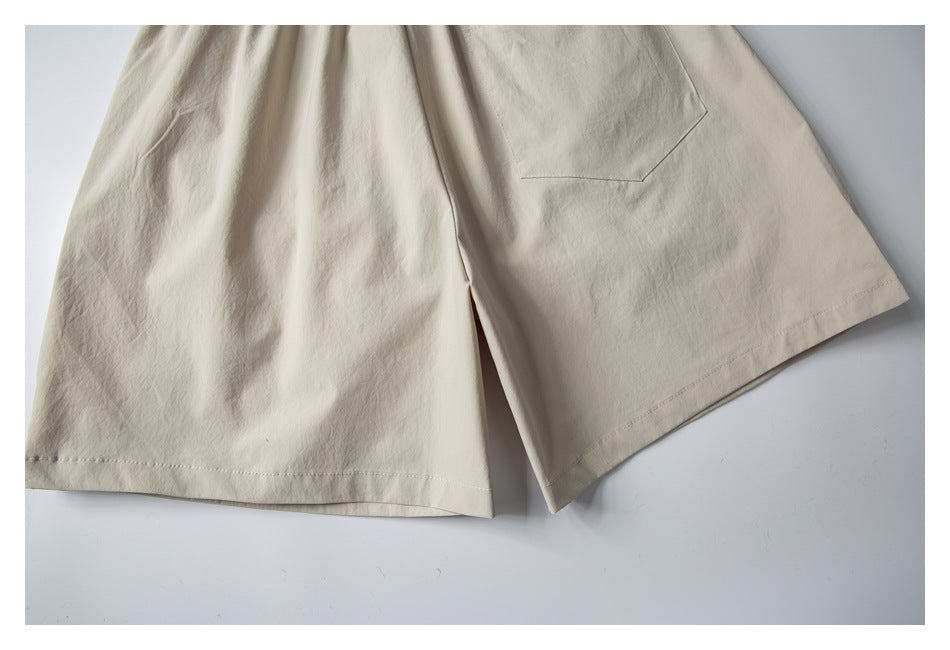 Close-up of the lower legs and stitched hems of cream shorts.