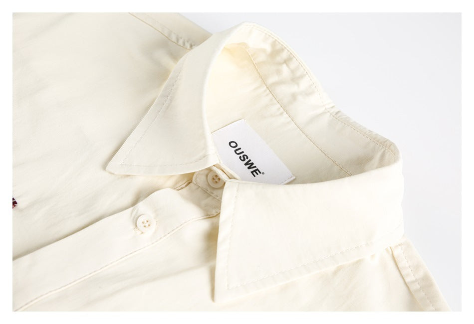 Close-up of the cream shirt's pointed collar, buttons, stitching, and sewn-in neck label.