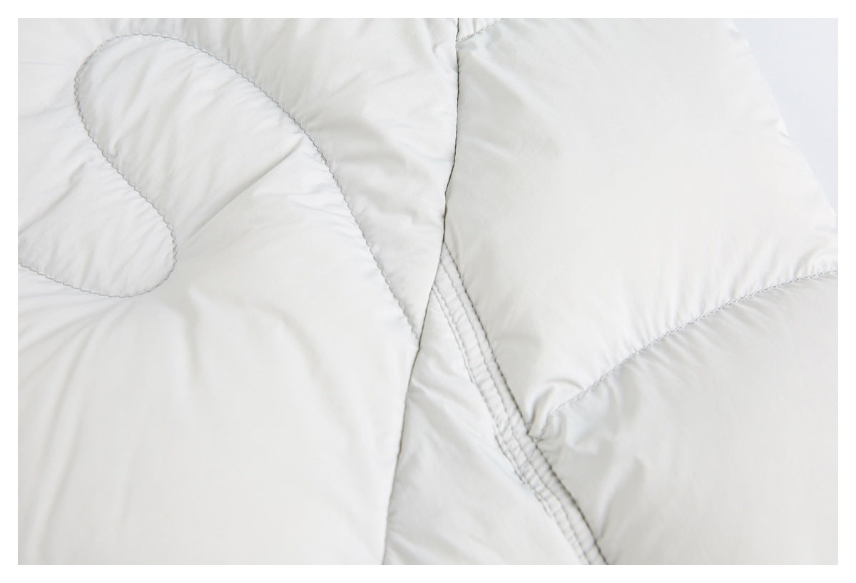 Close-up of ivory quilted fabric with curved stitching and a double-stitched seam.