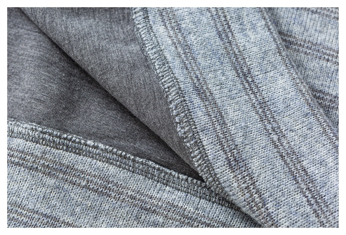 Close-up of gray striped knit fabric turned to show its inner seam and overlock stitching.