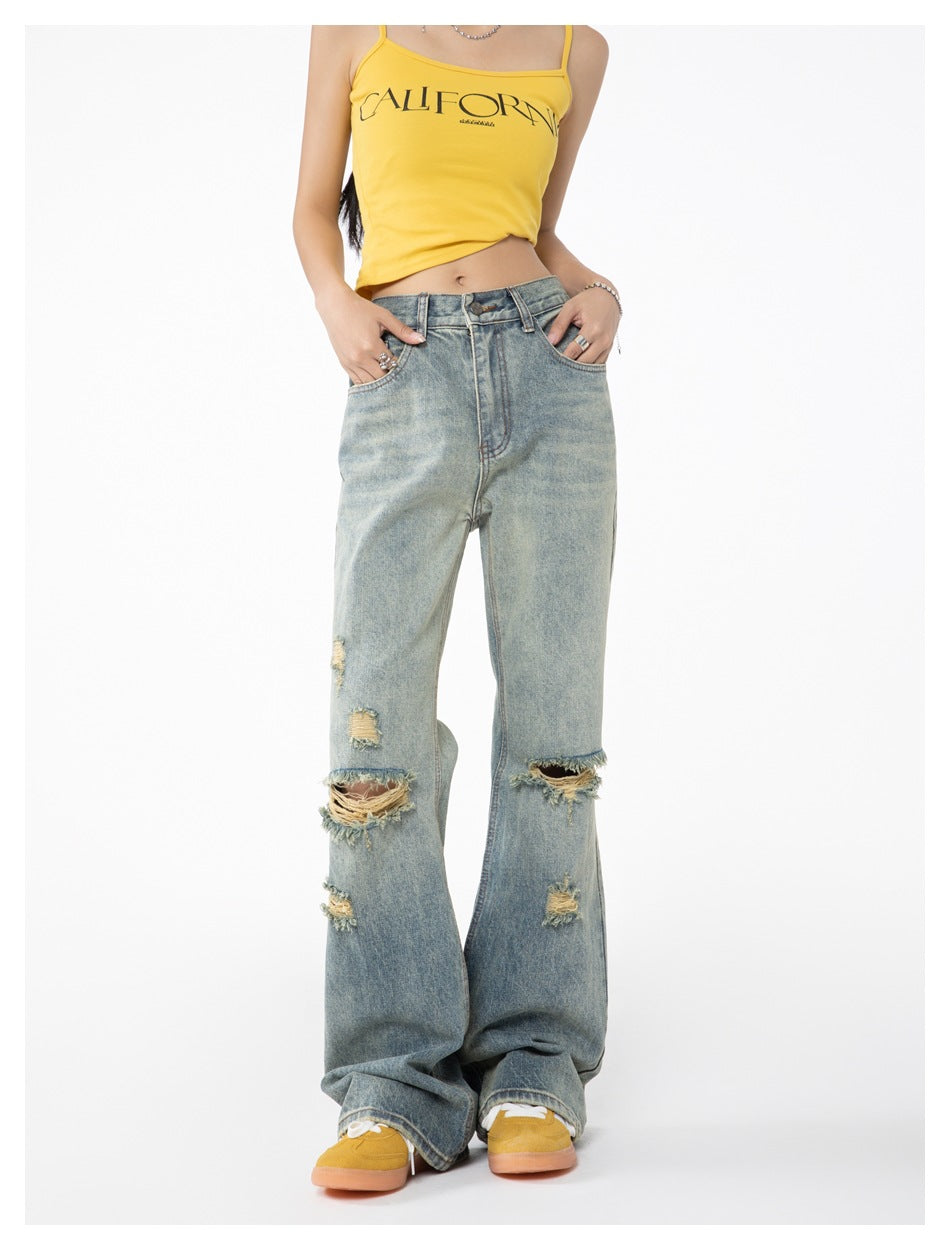 Close view of a model in light blue ripped flare jeans, hands in pockets, with a yellow camisole and yellow sneakers