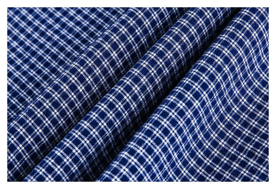 Close-up of navy fabric with a white and light-blue intersecting plaid pattern, draped in folds.