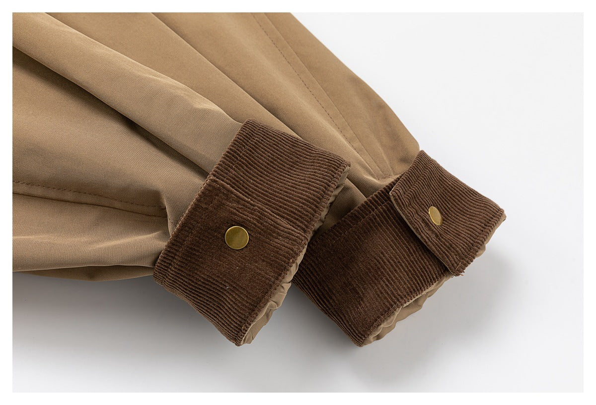 Close-up of tan jacket cuffs with dark brown ribbed trim and brass snaps.