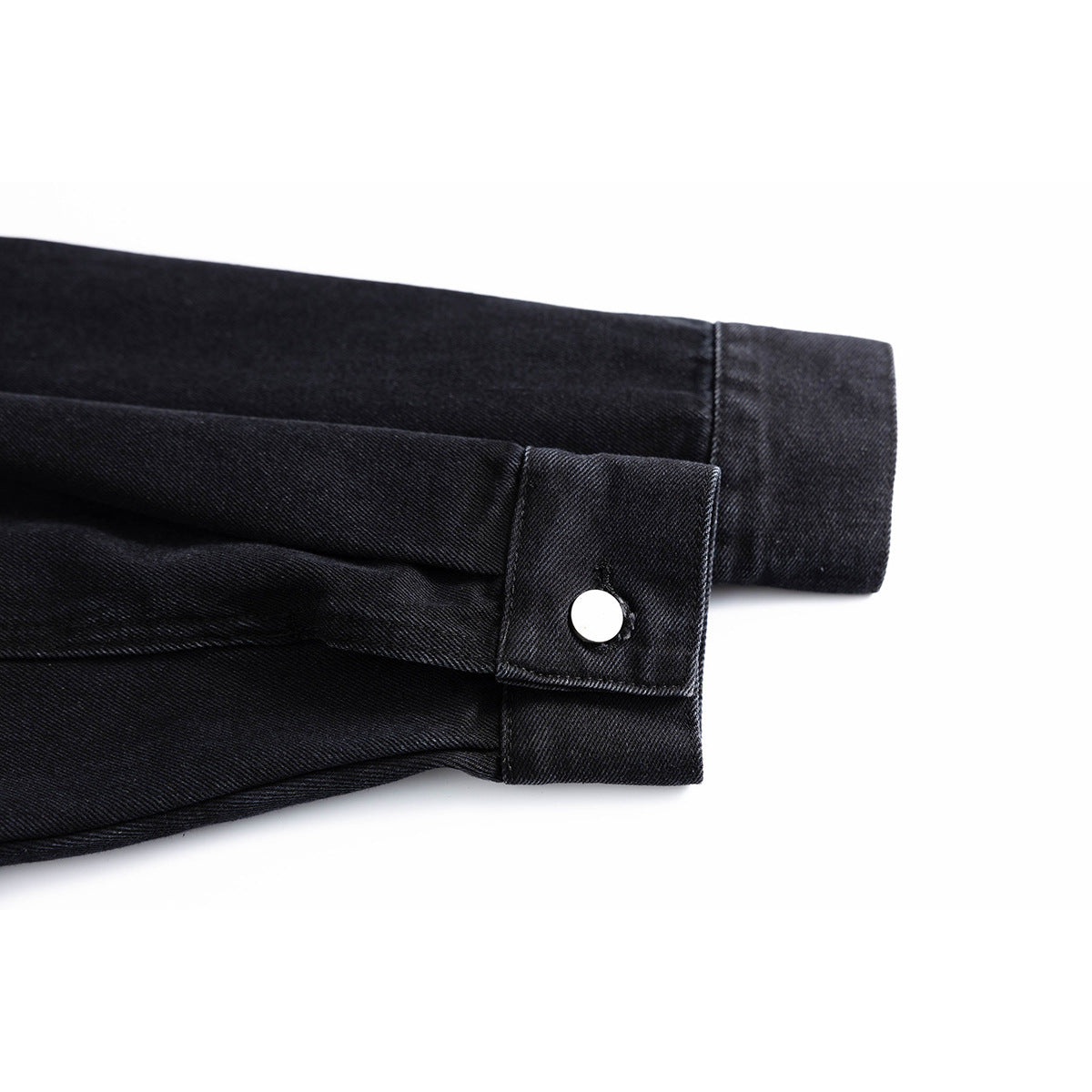 Close-up of a black jacket sleeve cuff with a silver snap button.