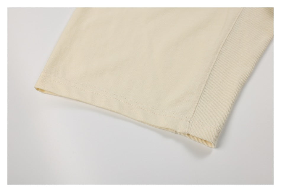 Close-up of an ivory garment edge with a stitched hem beside a ribbed panel.