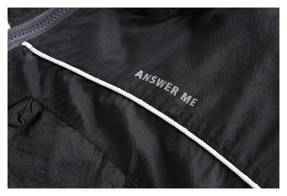 Close-up of white piping and ANSWER ME lettering on textured black jacket fabric.