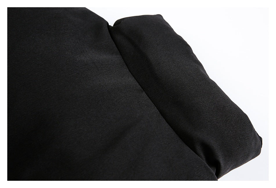 Close-up of a black garment panel beside a wide folded fabric edge.