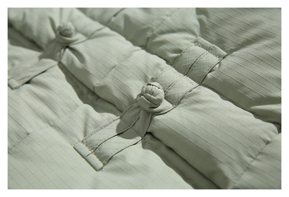Close-up of the pale sage jacket's fabric knot closure, stitching and fine grid texture.