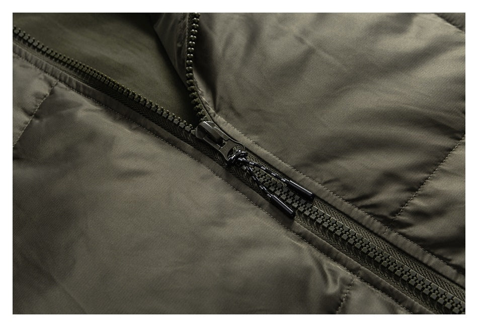 Close-up of an olive jacket's black zipper, pull tabs, and stitched panels.