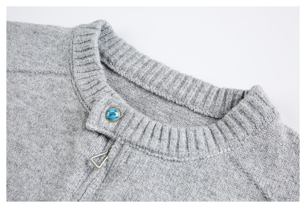 Light gray knit sweater neckline with ribbed trim, a blue button, and a small metal clasp.