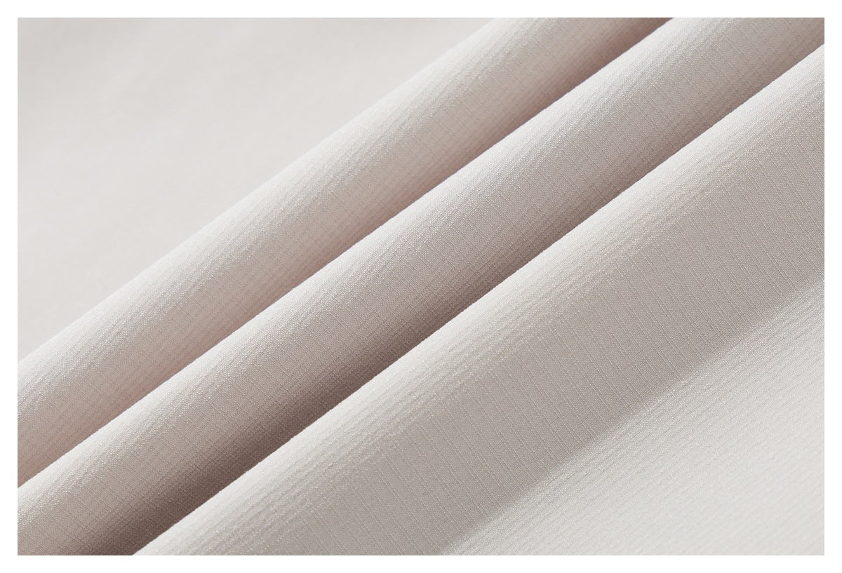 Close-up of light beige fabric arranged in soft folds, showing its subtle woven texture.