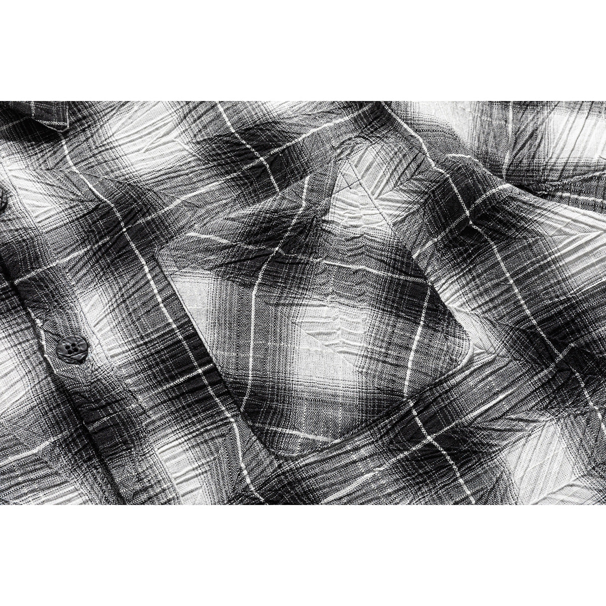 Close-up of a black, gray, and white plaid shirt showing a chest pocket and button.