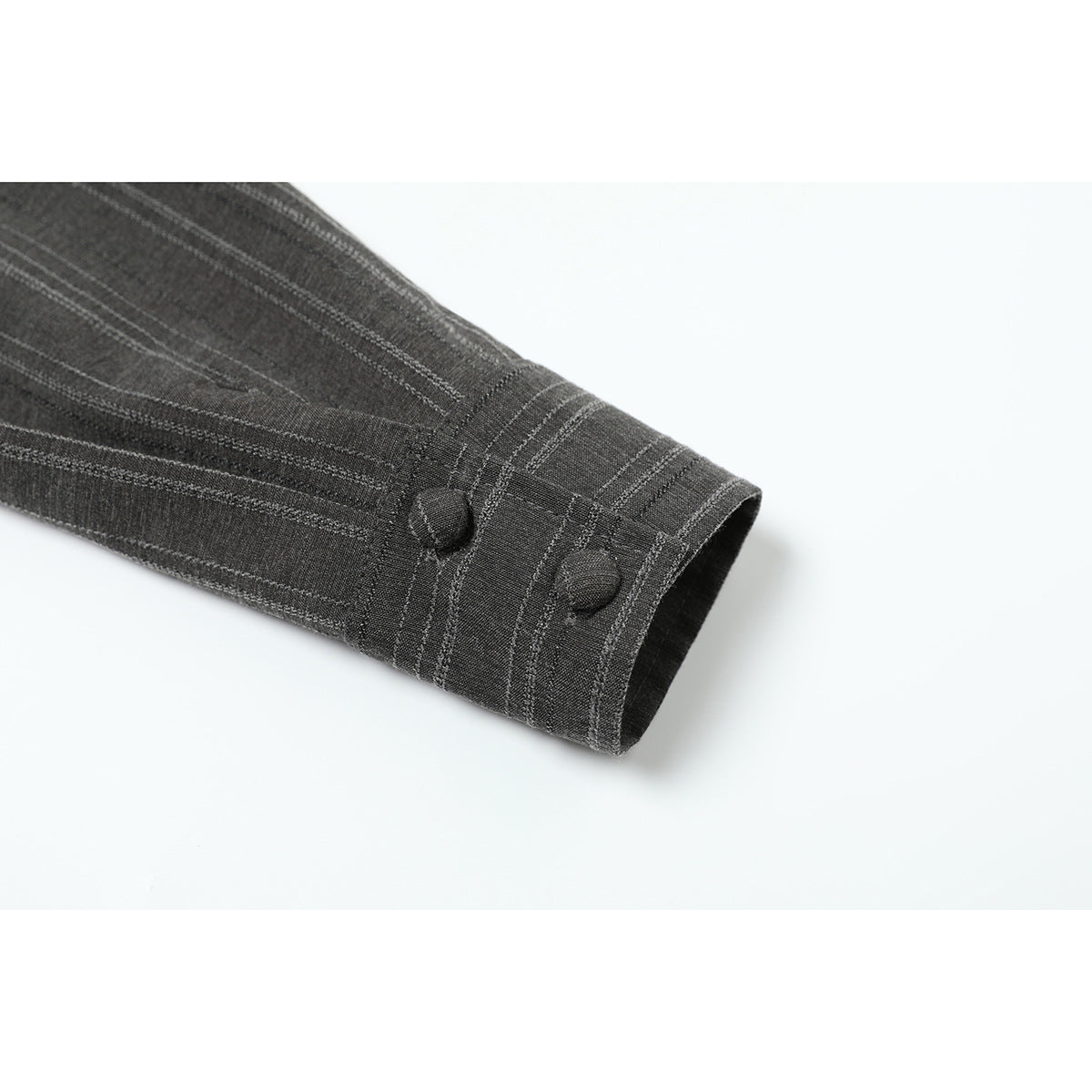 Close-up of a charcoal pinstriped sleeve ending in a cuff with two fabric-covered buttons.