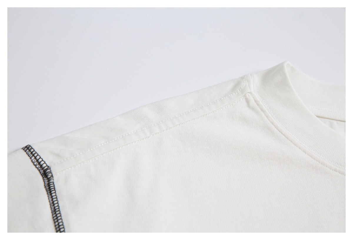 Close-up of the off-white T-shirt's shoulder seam and black overlock stitching at the sleeve edge.
