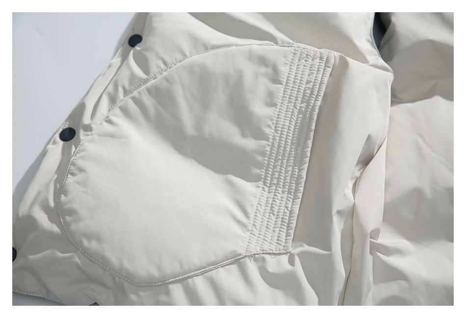 Close-up of a large white garment pocket with parallel rows of stitching and dark snap fasteners nearby.