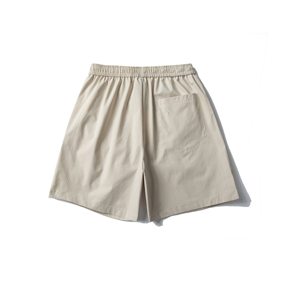 Back view of light beige shorts with an elastic waistband and a single patch pocket.