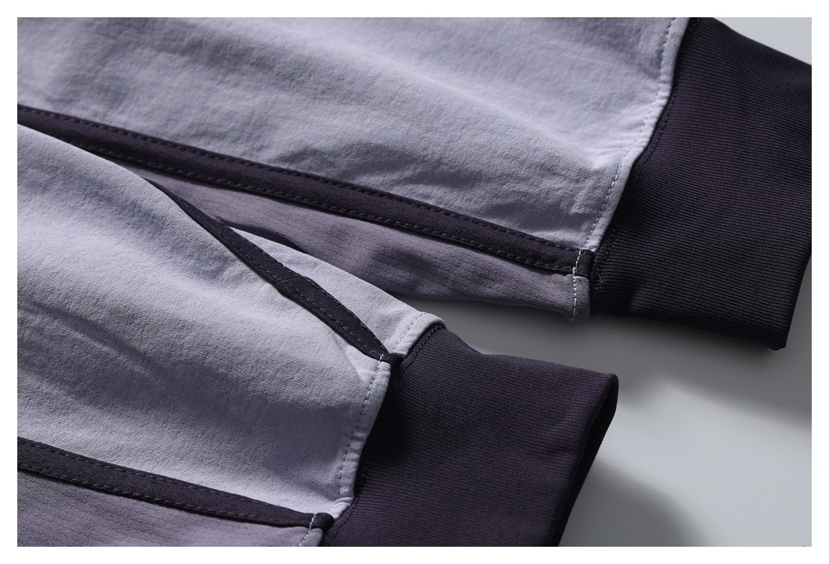 Close-up of the light gray shirt's dark contrast seams and ribbed cuffs.