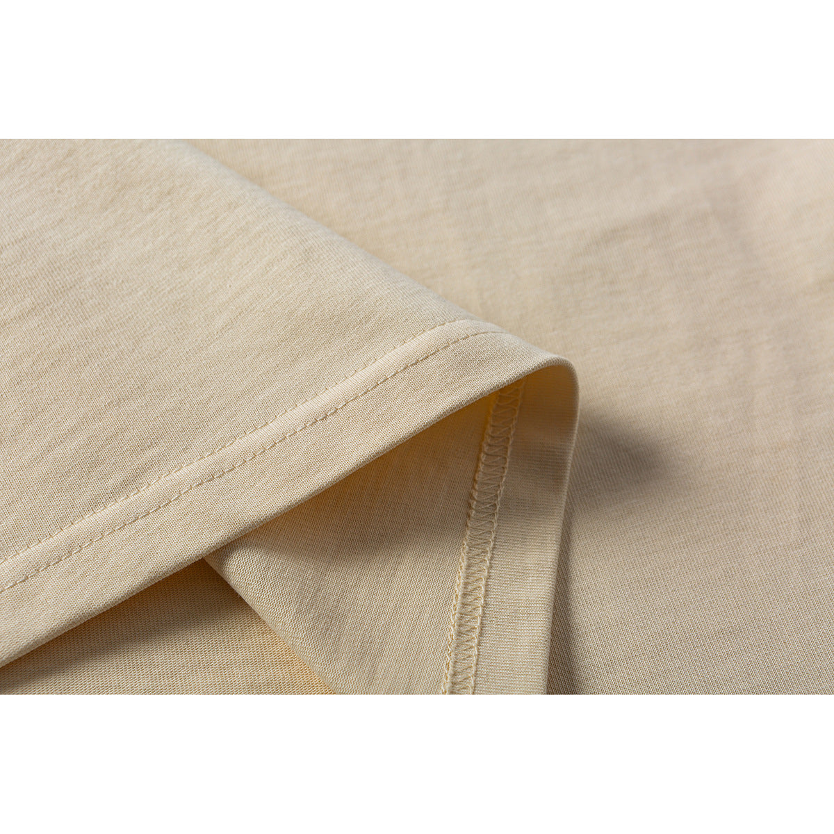 Close-up of the pale yellow T-shirt's stitched sleeve hem and fabric.
