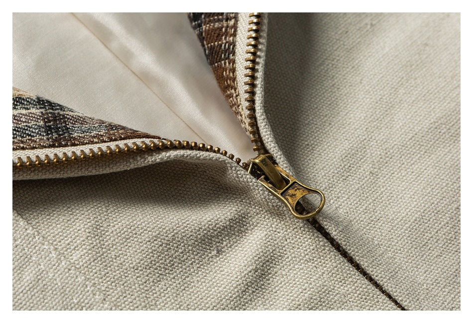 Close-up of a brass zipper on beige woven fabric with plaid lining.