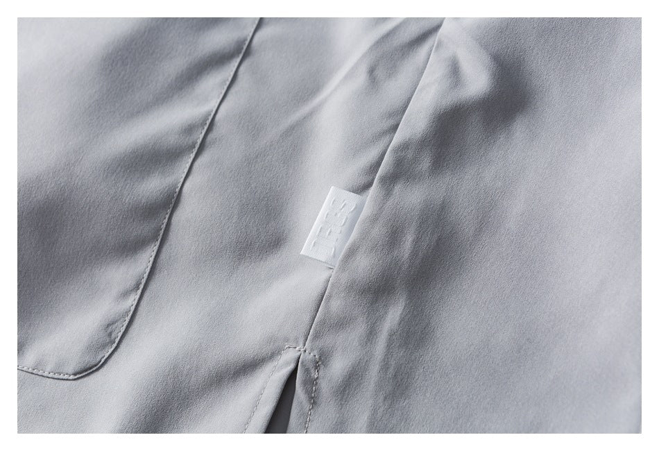 Close-up of a light gray garment seam with a small white fabric label.