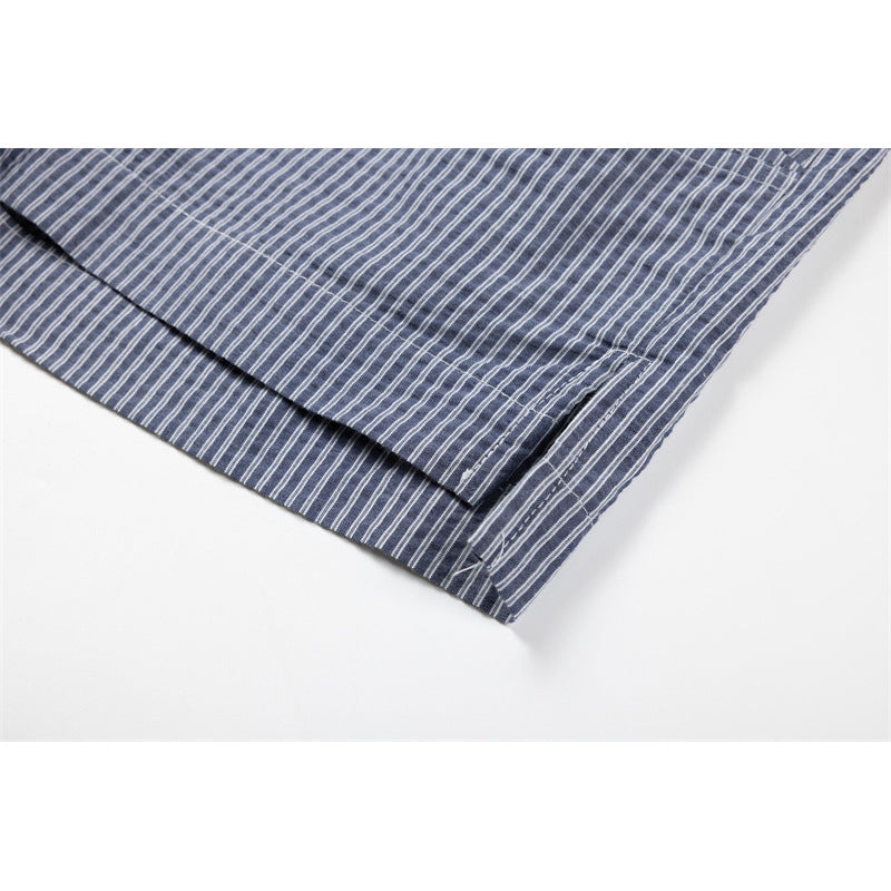 Close-up of the hem and side seam on a blue-gray shirt with fine white stripes.