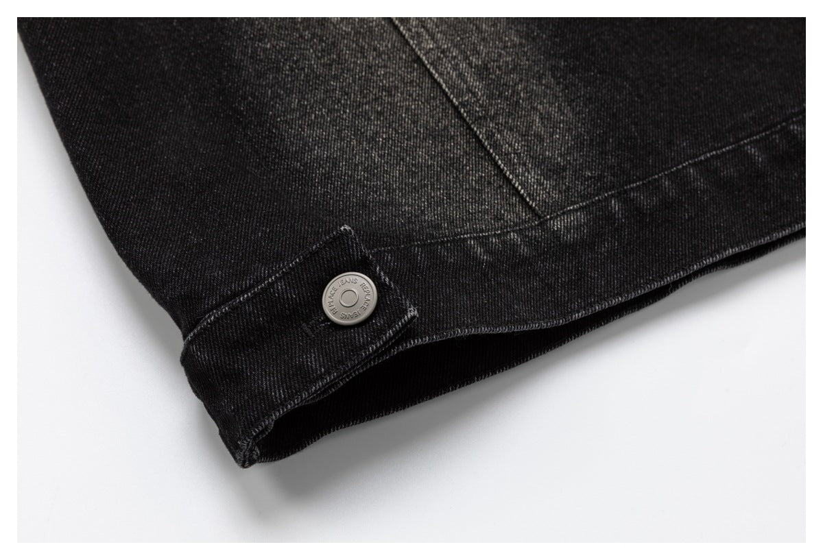 Close-up of a black denim jacket hem and buttoned side tab.