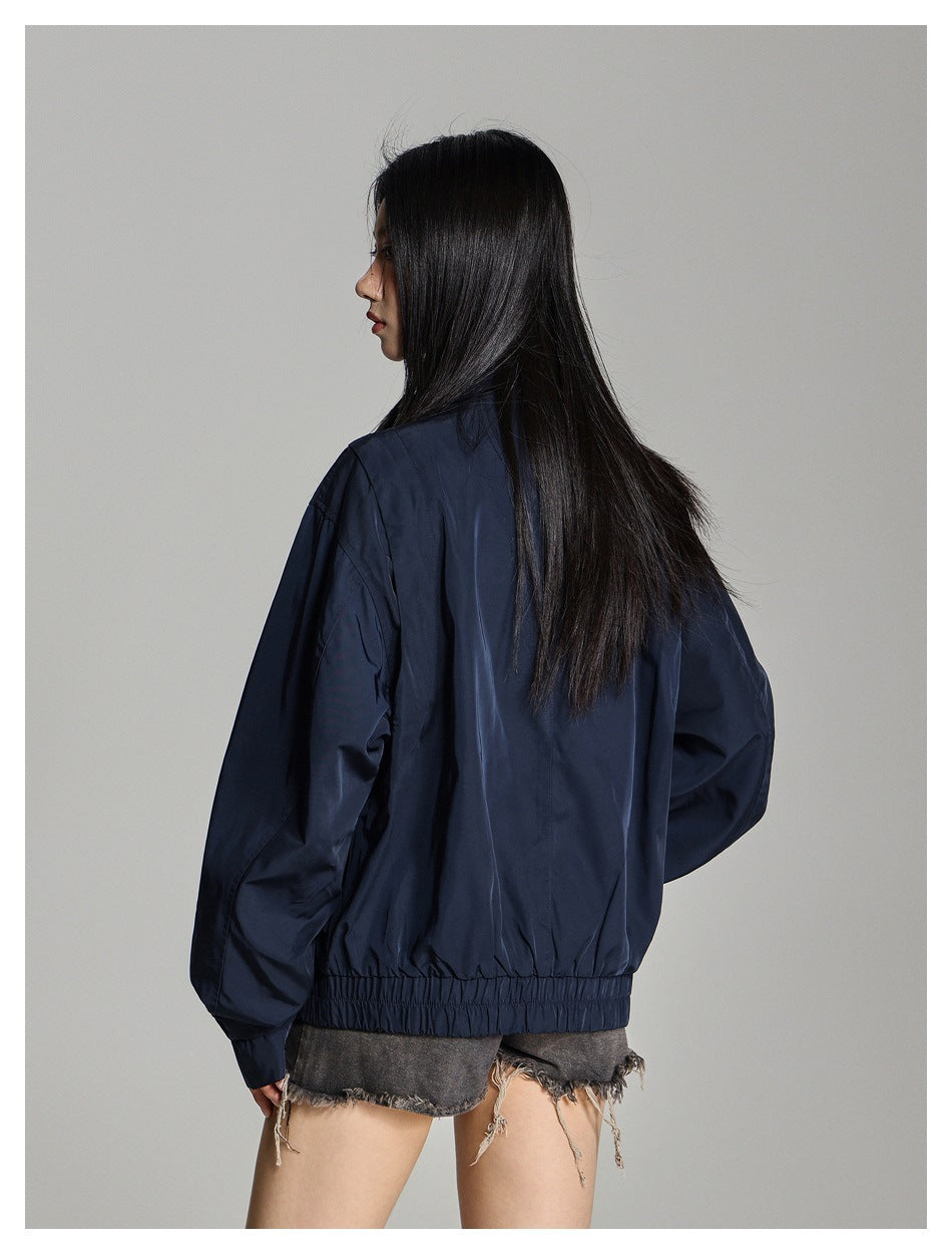 Rear view of a model wearing a navy oversized jacket with a gathered elastic hem and loose sleeves.