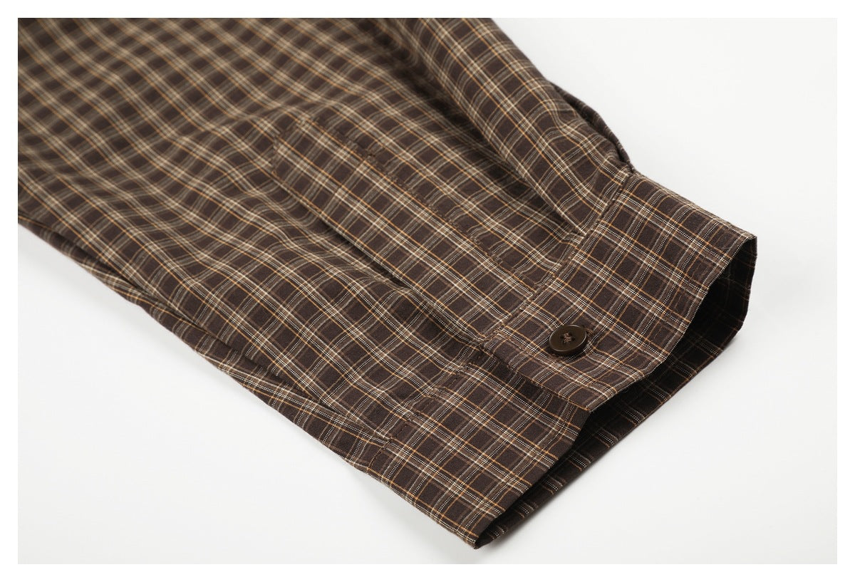 Close-up of a brown plaid shirt sleeve and buttoned cuff on a white background.