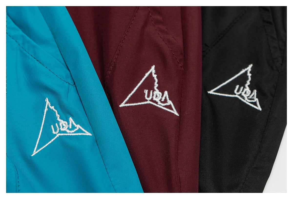 Close-up of turquoise, burgundy, and black shorts, each with a white embroidered triangular USA motif.