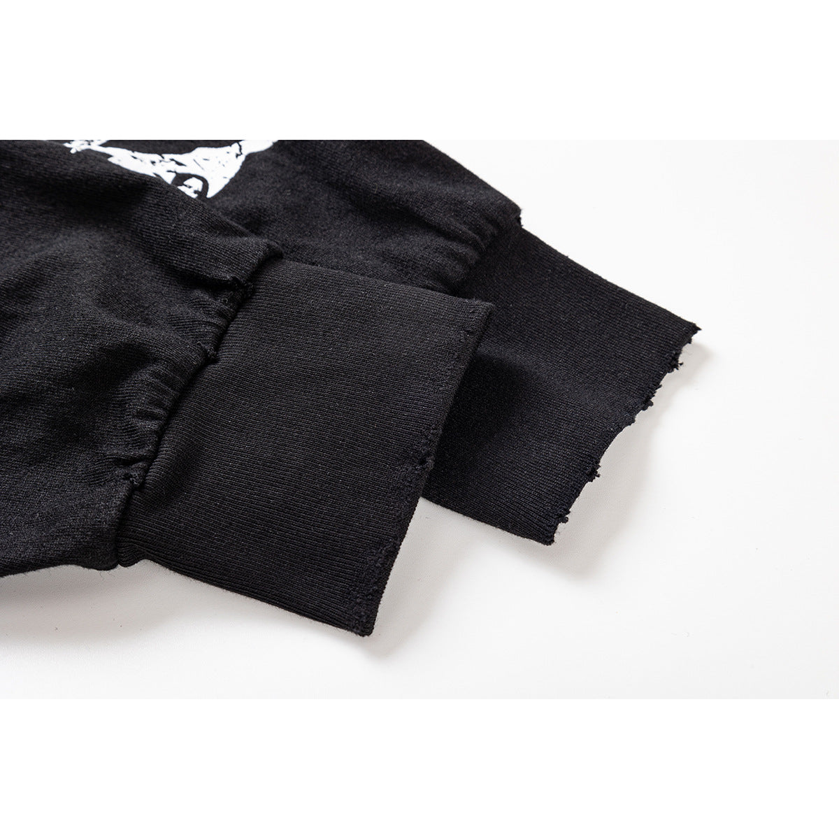 Close-up of a black shirt sleeve and wide ribbed cuff, with part of the white graphic visible.