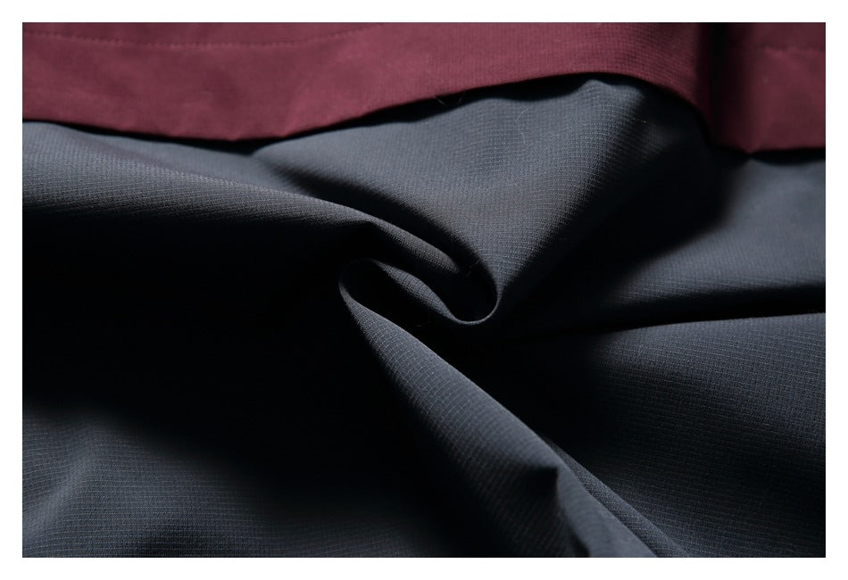Close-up of dark gray fabric beneath a burgundy garment panel, showing the surface texture.