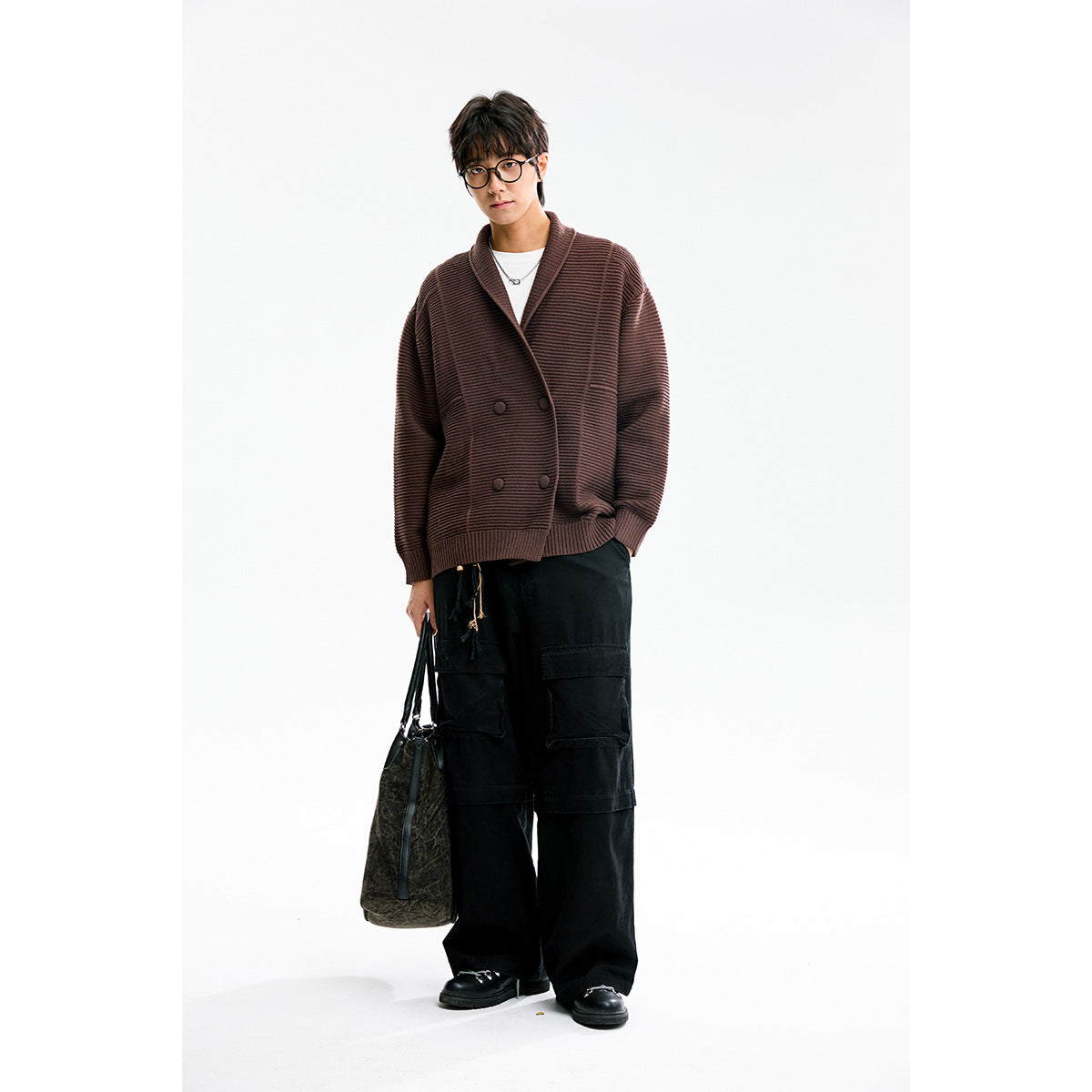 Model wearing a brown ribbed shawl-collar cardigan with black cargo trousers and carrying a dark bag.