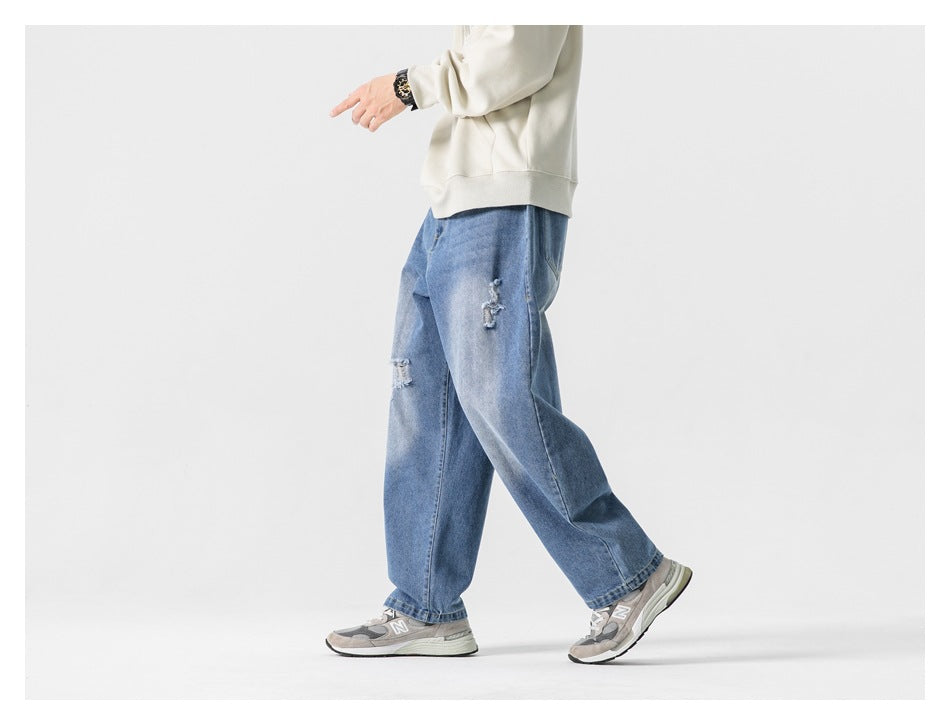 Side view of a model walking in relaxed blue jeans with distressed patches and a cream sweatshirt.